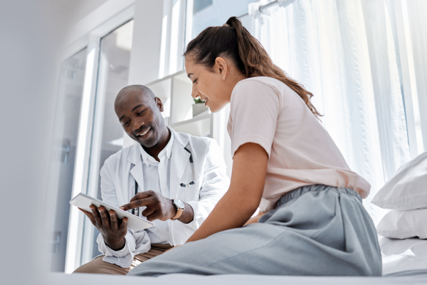 Image shows doctor showing information to patient on a tablet.