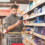 A grocery shopper uses their smartphone to compare the price of items online: retail pricing