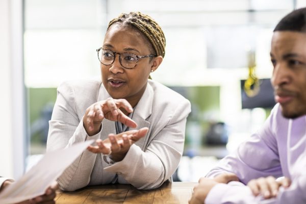 Businesswoman, professionally dressed, sitting at a table and leading a meeting in an office / marketing quotes