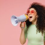 A woman shouting in a megaphone about referral programs for smbs