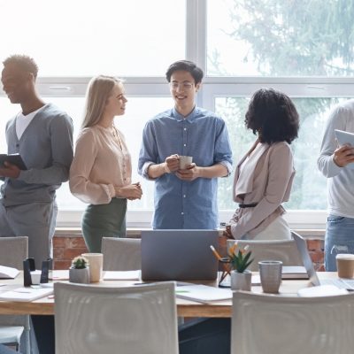 A small business team in a conference room talking with tablets and devices next to their table.