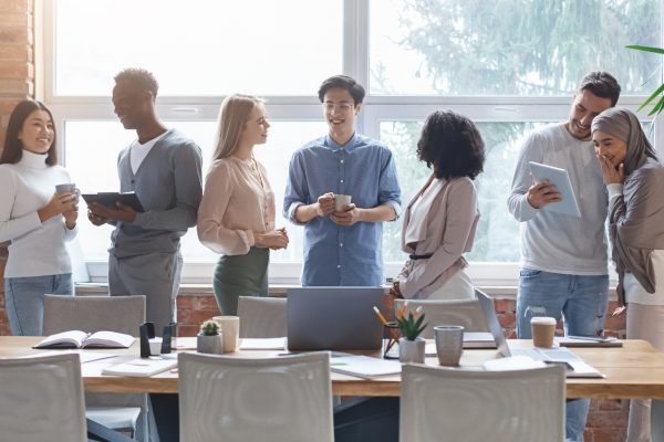 A small business team in a conference room talking with tablets and devices next to their table.