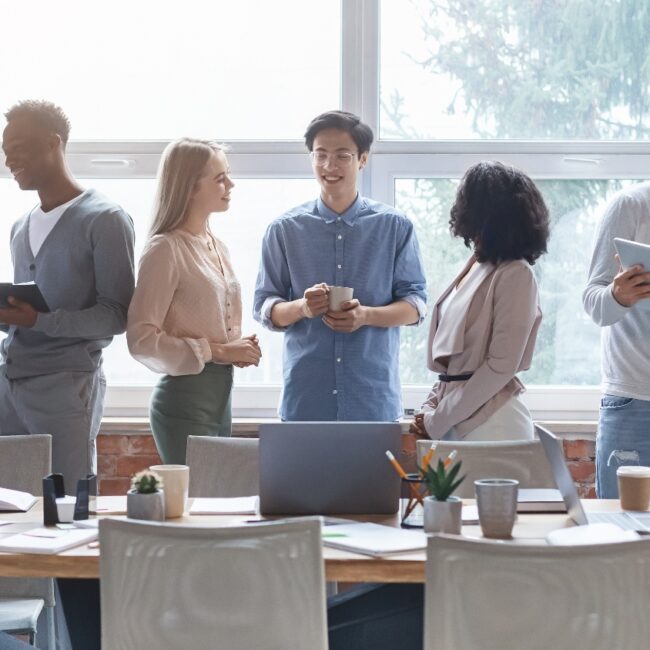 A small business team in a conference room talking with tablets and devices next to their table.