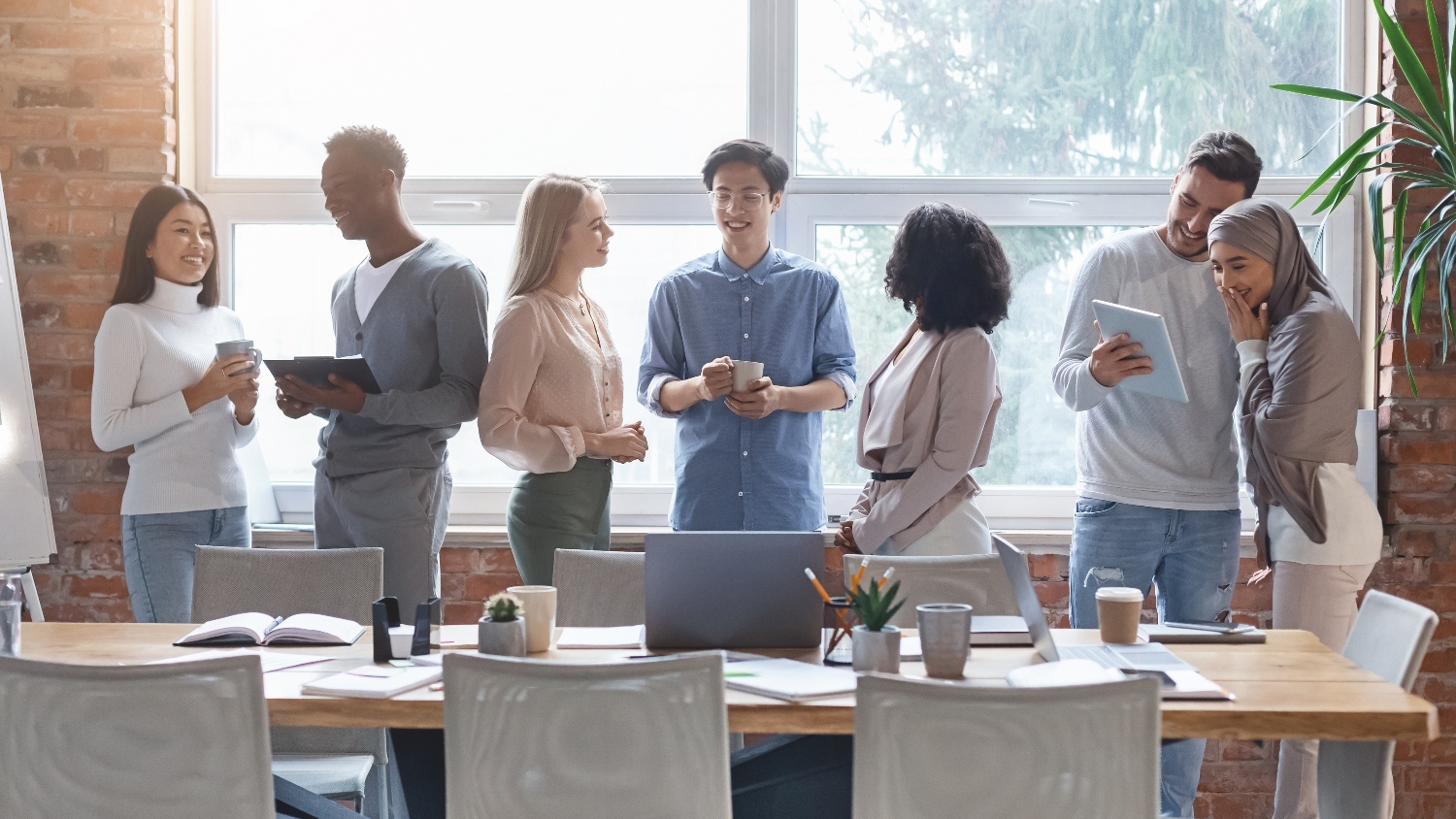 A small business team in a conference room talking with tablets and devices next to their table.