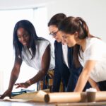 Photo showing a small business team of women setting up their minimum viable product on a tablet together.