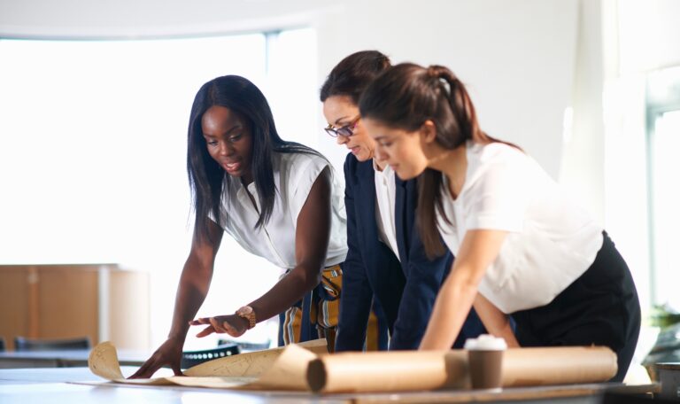 Photo showing a small business team of women setting up their minimum viable product on a tablet together.