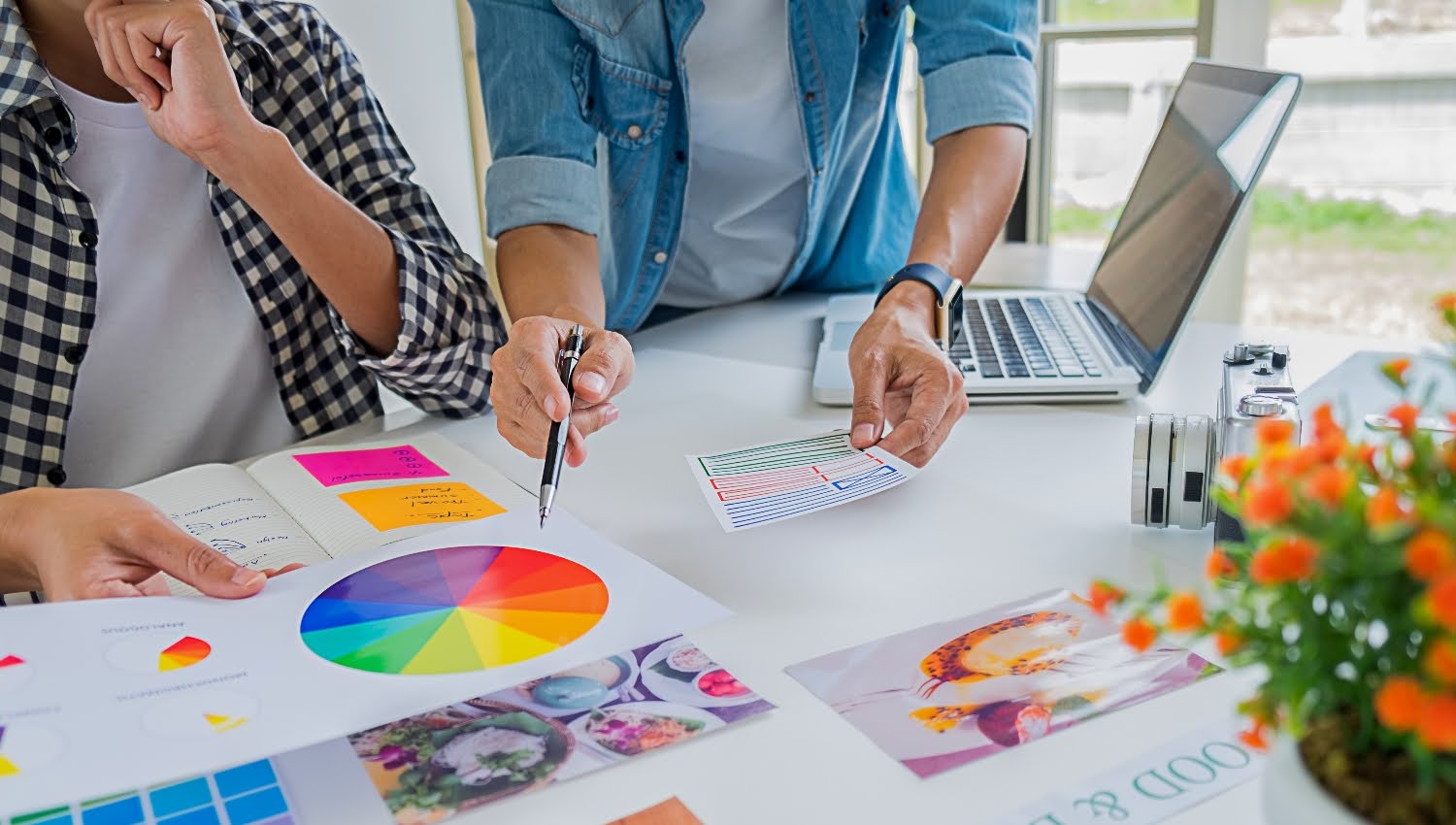 Two Small business owners building out its brand identity with the team on a table with charts and a whiteboard.