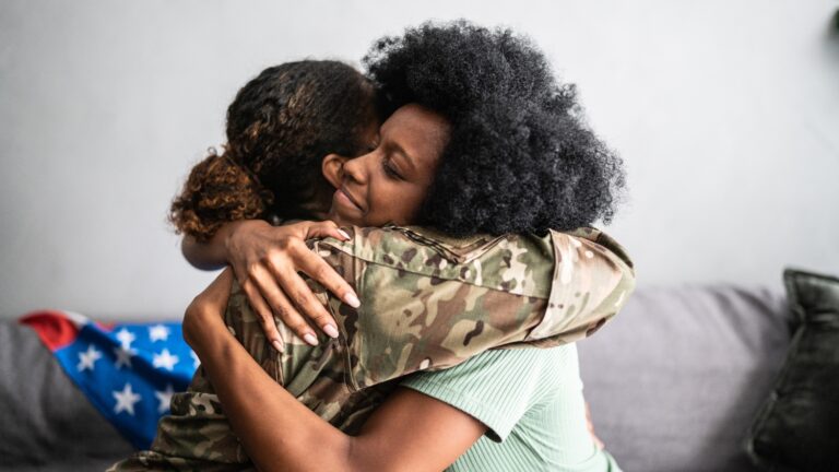 A photo of two women hugging, and one of them is wearing military gear.