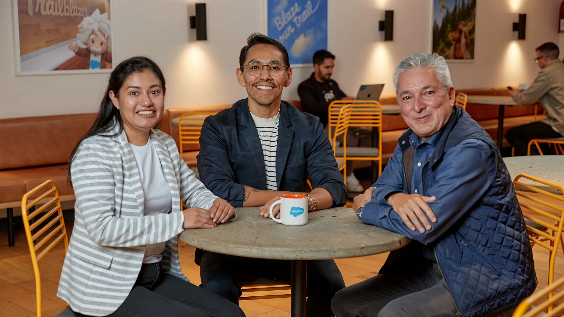 Three Salesforce employees spending time together in a cafeteria.