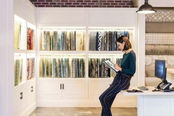 A woman sitting on a desk in front of a bookcase