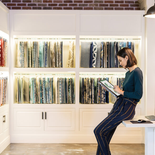 A woman sitting on a desk in front of a bookcase