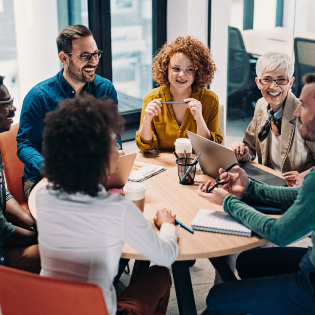 Group of business people having a meeting at a round conference table in a creative office.